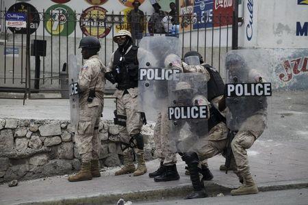National Police officers protect themselves from rocks thrown by protesters during a demonstration against the electoral process in Port-au-Prince, Haiti, January 22, 2016. REUTERS/Andres Martinez Casares