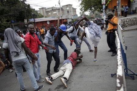 Protesters, who were mocking National Police officers (not pictured), simulate a beating during a demonstration against the electoral process in Port-au-Prince, Haiti, January 22, 2016.  REUTERS/Andres Martinez Casares