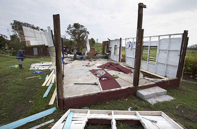 In this photo taken Wednesday, Feb. 24, 2016, a man surveys a destroyed building in Tavua, Fiji, after cyclone Winston ripped through the island nation. Fijians in remote places were being urged Thursday to immediately bury loved ones who died in the powerful cyclone rather than waiting for autopsies. (Brett Phibbs/New Zealand Herald via AP) NEW ZEALAND OUT, AUSTRALIA OUT