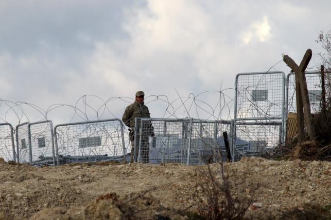 A Turkish soldier standing guard is seen from the Syrian town of Khirbet Al-Joz at the Turkish-Syrian border, in Latakia countryside, where internally displaced Syrian people are waiting to get permission to cross into Turkey, February 7, 2016. Picture taken February 7, 2016. REUTERS/Ammar Abdullah