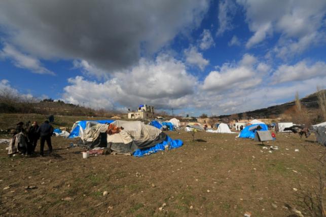 People stand outside tents housing internally displaced people in the town of Khirbet Al-Joz, in Latakia countryside, near the Syrian-Turkish border, Syria, February 7, 2016. REUTERS/Ammar Abdullah