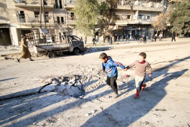 Boys run near a hole in the ground after airstrikes by pro-Syrian government forces in the rebel held al-Sakhour neighborhood of Aleppo, Syria February 8, 2016. REUTERS/Abdalrhman Ismail