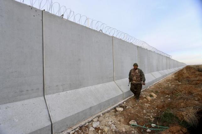 A Kurdish People's Protection Units (YPG) fighter walks near a wall, which activists said was put up by Turkish authorities, on the Syria-Turkish border in the western countryside of Ras al-Ain, Syria January 29, 2016. REUTERS/Rodi Said
