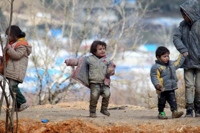 Internally displaced children, covered with mud, wait with their families as they are stuck in the town of Khirbet Al-Joz, in Latakia countryside, waiting to get permission to cross into Turkey near the Syrian-Turkish border, Syria, February 7, 2016. REUTERS/Ammar Abdullah