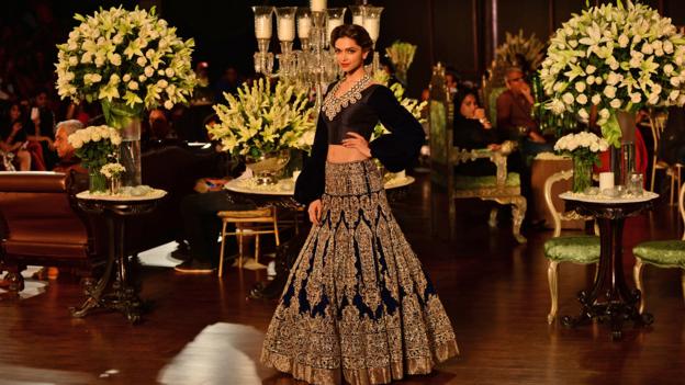 Indian Bollywood actress Deepika Padukone presents a creation by Indian fashion designer Manish Malhotra during the Grand Finale of PCJ Delhi Couture Week 2013 in New Delhi on August 4, 2013.  AFP PHOTO/ SAJJAD HUSSAIN        (Photo credit should read SAJJAD HUSSAIN/AFP/Getty Images)