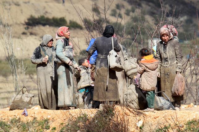 Internally displaced people, covered with mud, wait as they are stuck in the town of Khirbet Al-Joz, in Latakia countryside, waiting to get permission to cross into Turkey near the Syrian-Turkish border, Syria, February 7, 2016. REUTERS/Ammar Abdullah