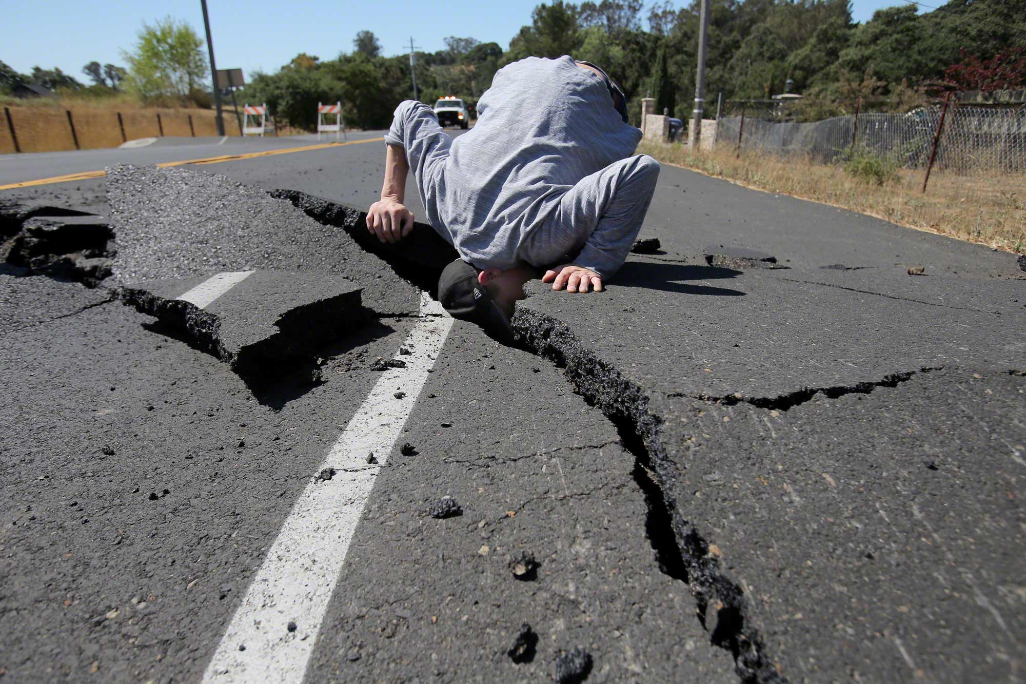 24 Aug 2014, Napa, California, USA --- Aug. 24, 2014 - Napa, California, U.S. - NICHOLAS GEORGE of Carneros cranes his head down into a deep fissure in front of his house on Old Sonoma Road caused by a 6.0 earthquake early Sunday morning. (Credit Image: &copy; Napa Valley Register/ZUMA Wire) --- Image by &copy; Lisa James/Register/ZUMA Press/Corbis