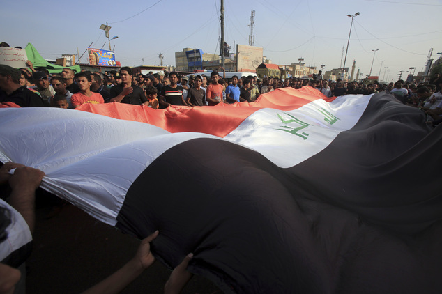 Protesters wave a giant Iraq flag as they chant anti-government slogans during a demonstration against the security forces' failure to protect them from car bombs at the site of yesterday's car bomb attack in the Iraqi capital's eastern district of Sadr City, Iraq, Thursday, May 12, 2016. (AP Photo/Karim Kadim)