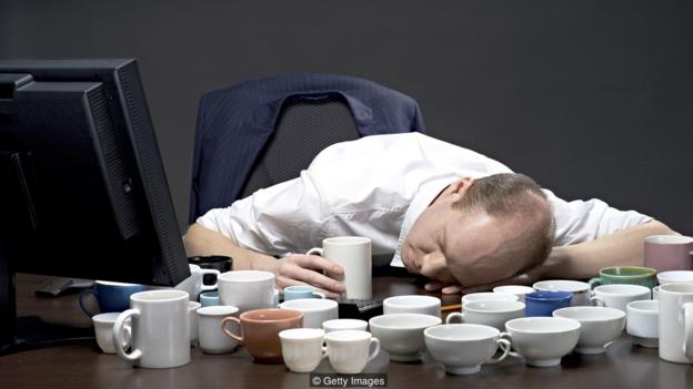 Exhausted man sleeping among coffee cups after long day of work