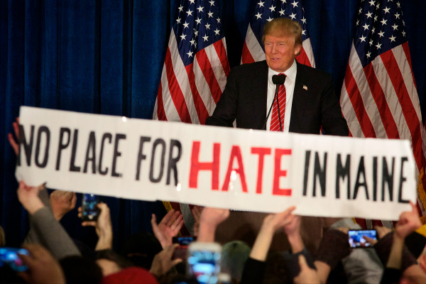 PORTLAND, MAINE -- 03/03/16 -- A protestor unfurls a banner at a Donald Trump campaign rally in Portland on Thursday. The proceedings were interrupted four times by similar protests. Troy R. Bennett | BDN