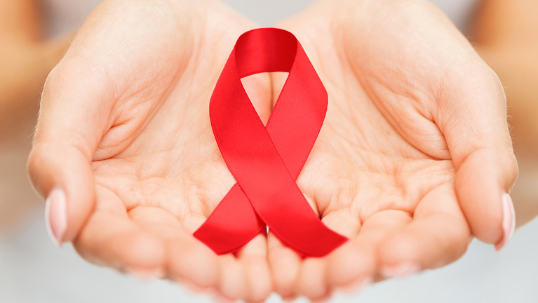 Красная лента- символ борьбы против СПИДа в женских ладонях